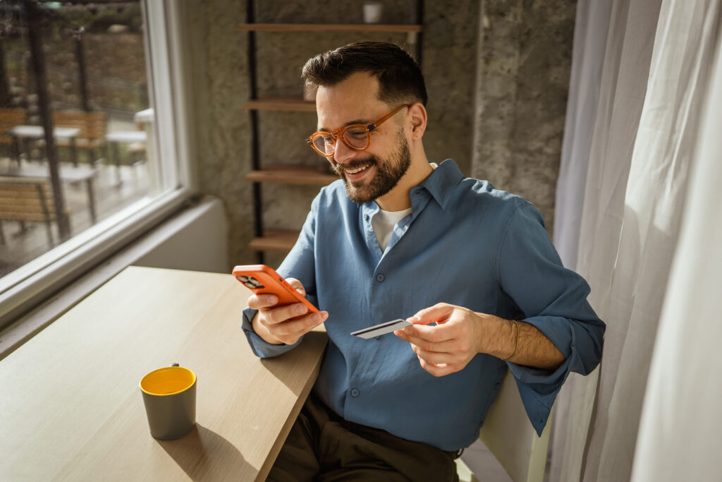 Mann mit Smartphone und KT Bank Karte